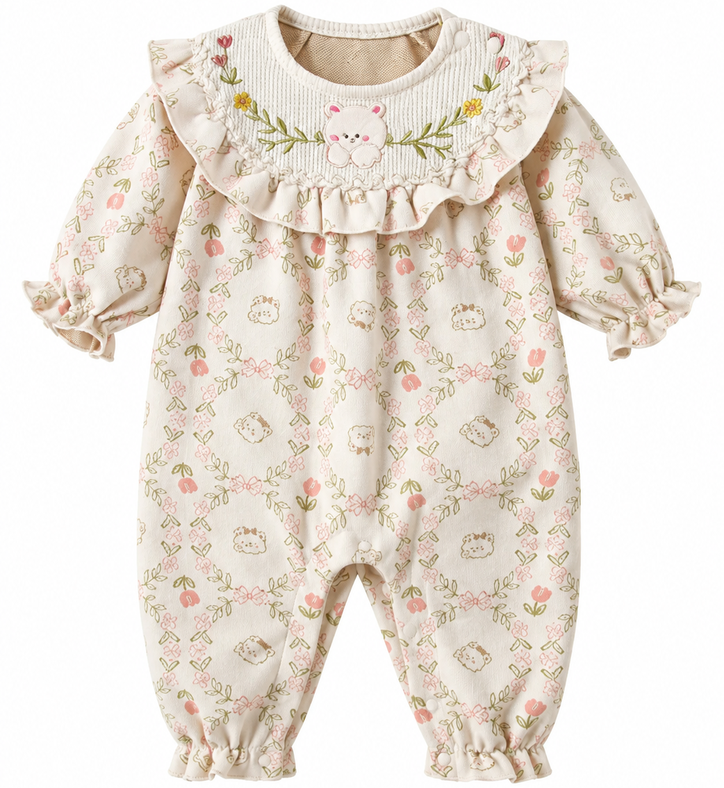 A baby's long-sleeve romper in cream with a delicate pink and green floral print, featuring a large ruffled collar decorated with a small embroidered bunny face.